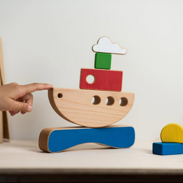 Wooden toy boat with colorful blocks on a light surface